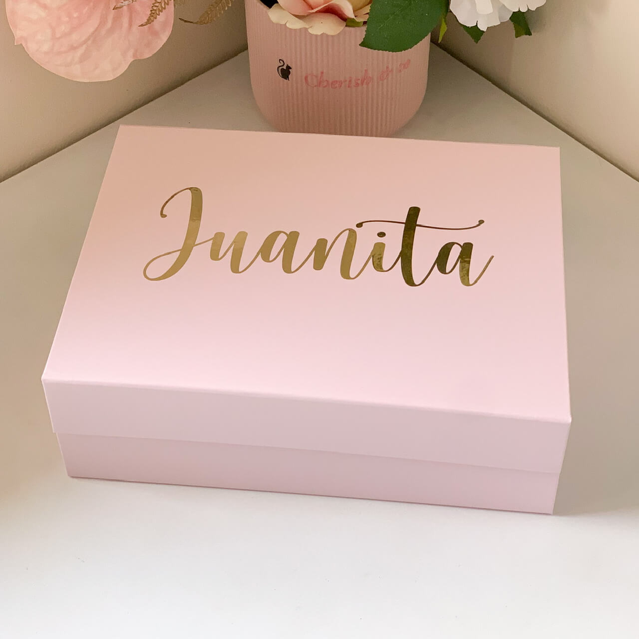 Pink box with 'Juanita' written in gold on a light background
